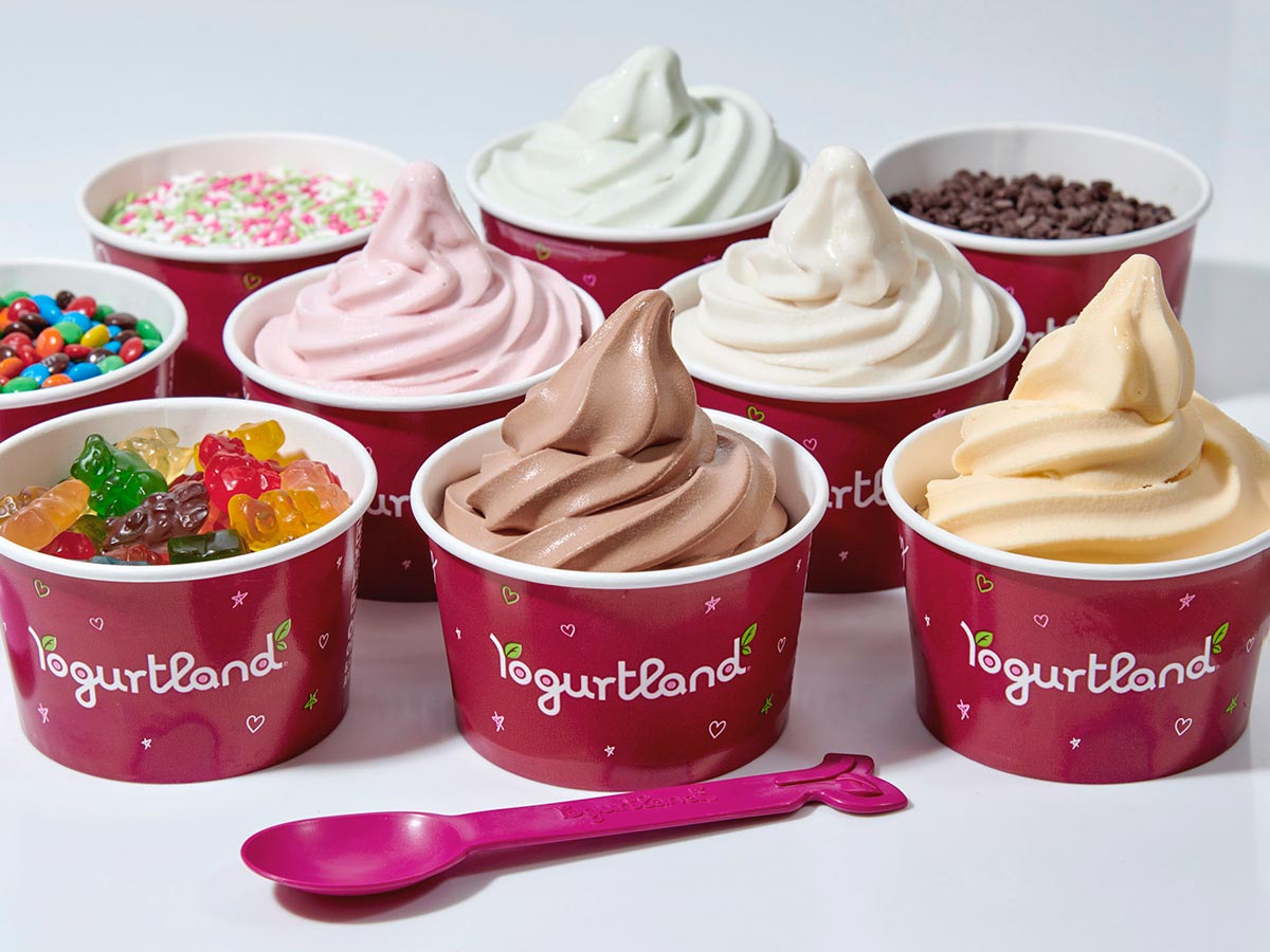 A group of Yogurtland cups of frozen yogurt and toppings